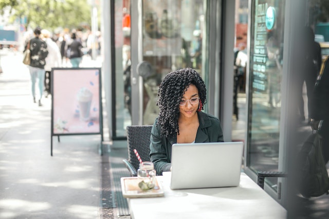 a california landlord with long curly hair sits outside a cafe and emails their tenant a security deposit return notice